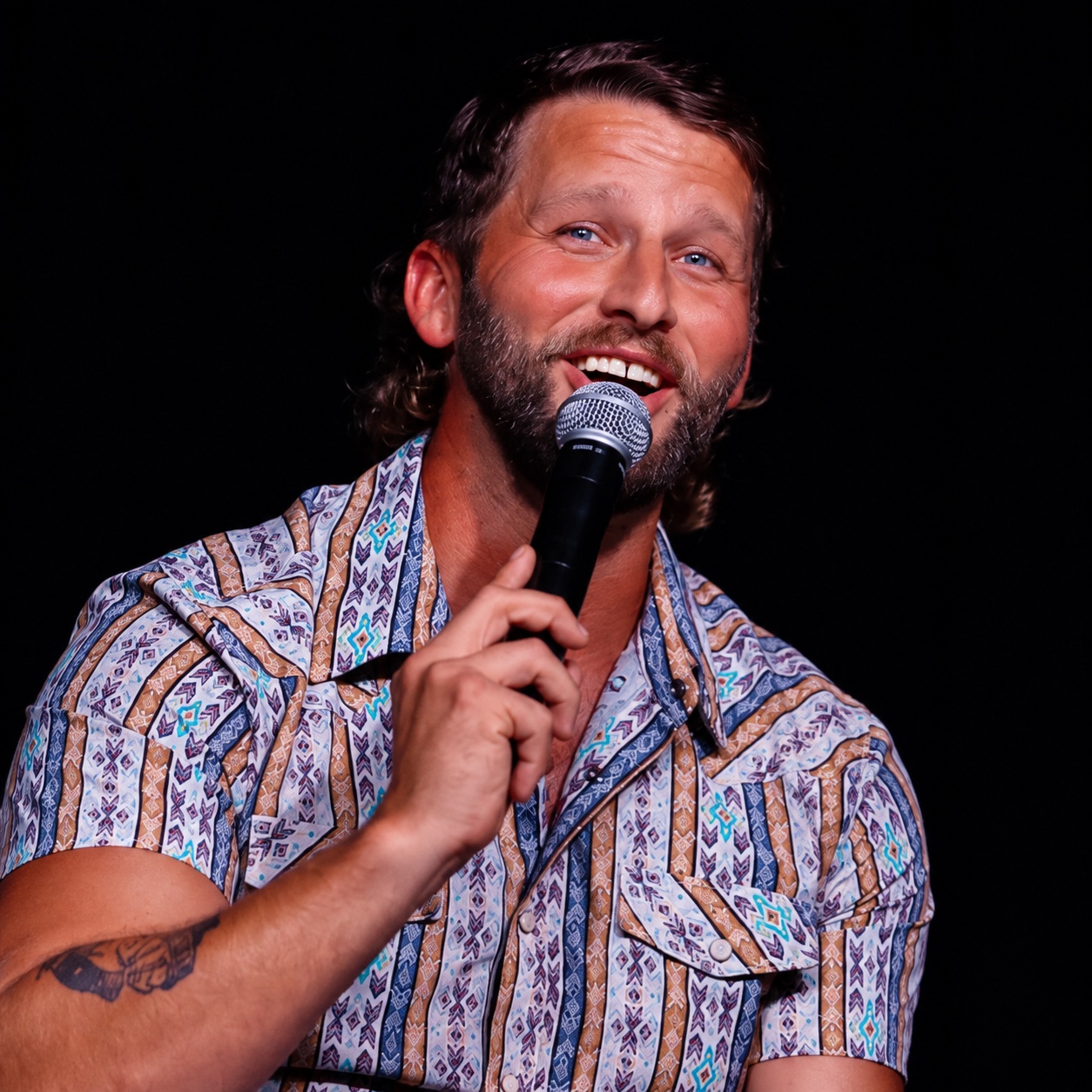 Dustin Sims smiling onstage with a microphone.